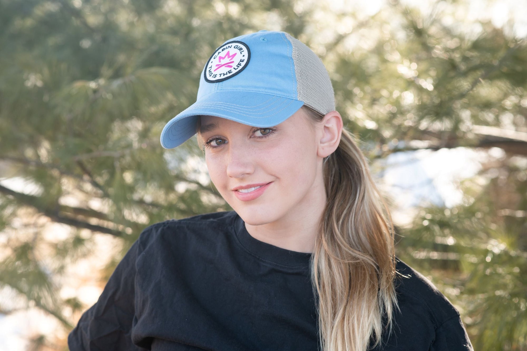 Girl in blue baseball cap at a cabin in the woods